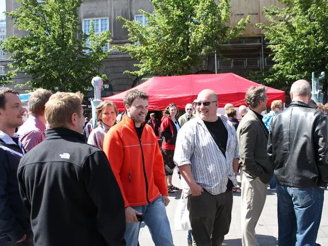 In the picture there is a road, on the road there are many people present, beside there is a tent,...