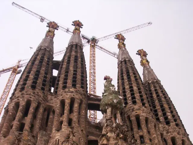 In the picture I can see a building, towers and jobs. In the background I can see the sky.
