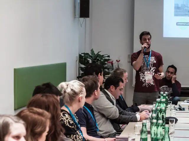 this is a picture of an auditorium. Here we can see a table and mobiles, water bottles on it. We...