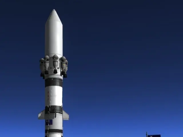 In this image, we can see a rocket. There is a flag on the right side of the image. There is a sky...